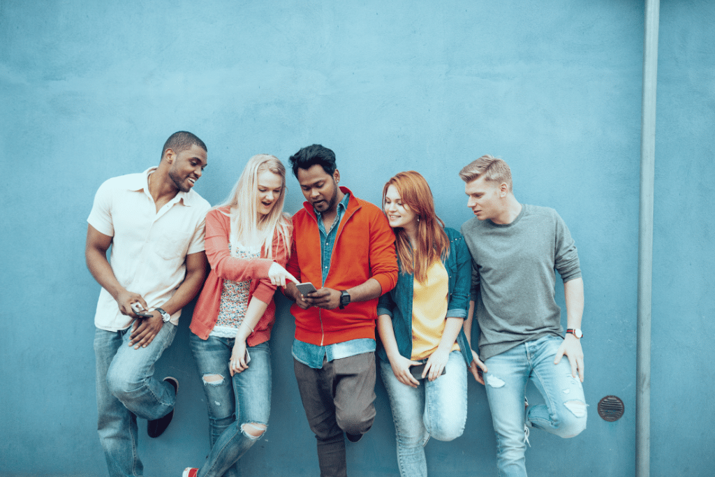 five generation z young adults standing together looking at a money related application on a cell phone