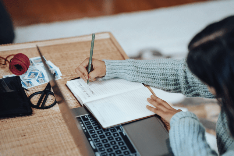 woman writing in notepad setting financial goals